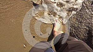 Feet view of a man walking on the sand of a beach