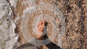 Feet walking barefoot on sandy beach in real time