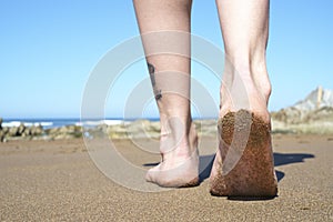 Feet walking on beach closeup.