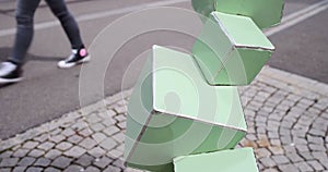 Feet walking past a green cube structure in Zurich