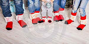 Feet wearing Christmas socks on wood floor. Happy family at home. Xmas holidays concept