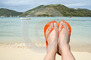 Feet Wearing Orange Flip Flop on a Beach 1