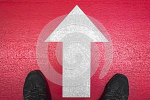 Feet and white arrow on red background
