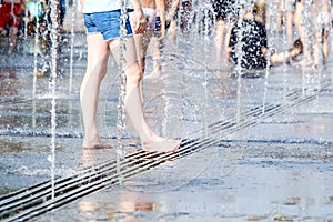 Feet of a woman barefoot in the spray of jets of water from the fountain.