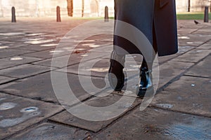 feet of woman in a black shoes on the city street on cold day