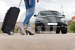 Feet of a woman carrying a black trolley case