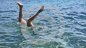 Feet of a woman diving into sea water