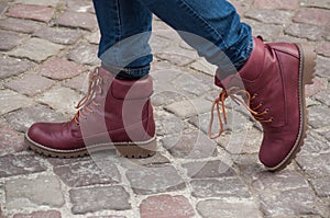 Feet of woman with red winter boots on cobblestone in the street