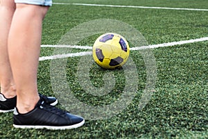 Feet of woman in sneakers and soccer ball