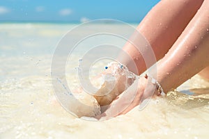 Feet of a woman in the spray of clean sea water.