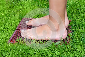 Feet of a woman standing on a sadhu yoga board with nails