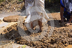 Feet of a woman while trampling the soil to build a wall