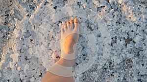 The feet of a woman walk along white salty crust on salt lake extraction factory Sivash in Kherson region, Ukraine