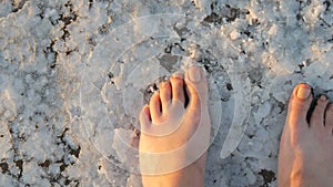 The feet of a woman walk along white salty crust on salt lake extraction factory Sivash in Kherson region, Ukraine