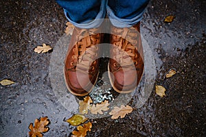 Feet of a woman walking along asphalt road in autumn forest