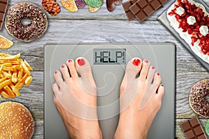 Feet of woman on weighting scale asking for help to avoid the temptation to eat unhealthy food photo