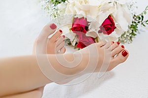 Feet of women with red toenails after pedicure