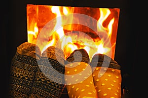 Feet in wool socks of couple lovers warming by cozy fire.
