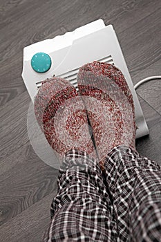 Feet with wool socks and electric heater