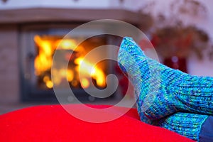 Feet in woollen blue socks by the fireplace.