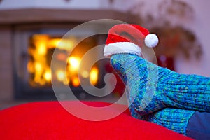 Feet in woollen blue socks and Santa hat .