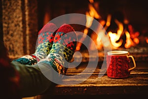 Feet in woollen socks by the Christmas fireplace. Woman relaxes