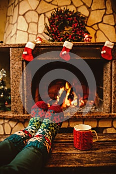 Feet in woollen socks by the Christmas fireplace. Woman relaxes