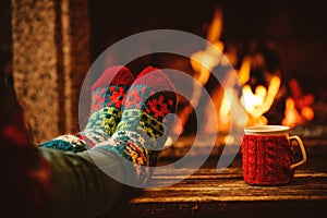 Feet in woollen socks by the Christmas fireplace. Woman relaxes