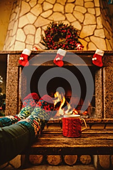 Feet in woollen socks by the Christmas fireplace. Woman relaxes photo