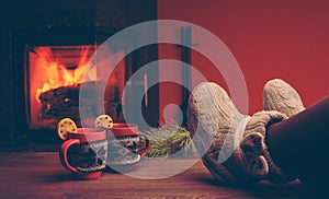 Feet in woollen socks by the Christmas fireplace. Woman relaxes