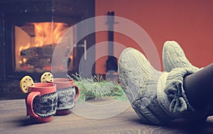 Feet in woollen socks by the Christmas fireplace. Woman relaxes