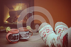 Feet in woollen socks by the Christmas fireplace. Woman relaxes