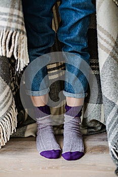 Feet in woollen socks. Woman is relaxing with a cup of hot drink and warming up her feet in woollen socks.