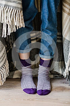 Feet in woollen socks. Woman is relaxing with a cup of hot drink and warming up her feet in woollen socks.