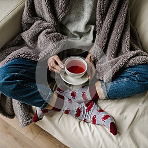 Feet in woollen socks. Woman is relaxing with a cup of hot drink and warming up her feet in woollen socks.