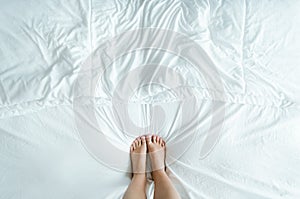 Feet in a wrinkly white bed