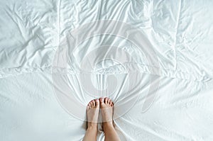 Feet in a wrinkly white bed