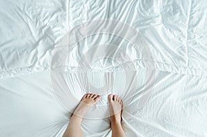 Feet in a wrinkly white bed