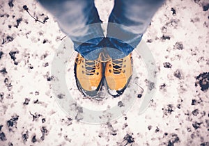 feet in yellow trekking boots on snow, a trip in winter, a picture from above