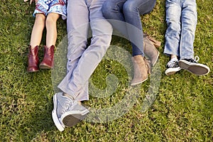 Feet of a young family lying on grass in a park, crop shot