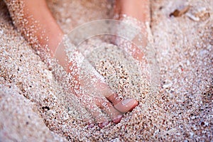 Feet of a young girl in the sand by the ocean closeup