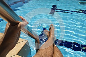 The feet of a young man in a swimming pool in summer, Spain