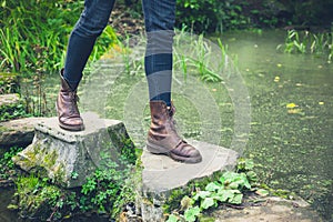 Feet of young person on stepping stones in a pond.