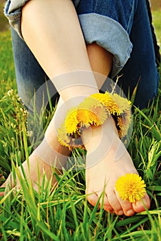 Feet of Young Woman on the Grass adorned with Dandelions