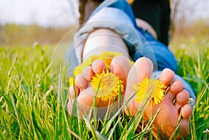 Feet of Young Woman on the Grass adorned with Dandelions