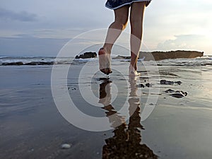 Feet of young woman walking on beach with the shadow of the water reflection background.
