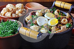 Feijao Tropeiro typical dish of Brazilian cuisine, made with beans, bacon, sausage, collard greens, eggs, on rustic wooden table