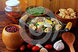 Feijao Tropeiro typical dish of Brazilian cuisine, made with beans, bacon, sausage, collard greens, eggs, on rustic wooden table photo