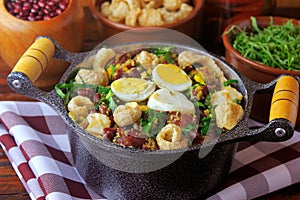 Feijao Tropeiro typical dish of Brazilian cuisine, made with beans, bacon, sausage, collard greens, eggs, on rustic wooden table photo