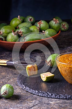 Feijoa jam in a glass bowl with cut green feijoa fruits. Natural homemade dessert. Rural still life